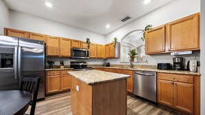 Una cocina moderna con armarios de madera, electrodomésticos de acero inoxidable y una isla central.