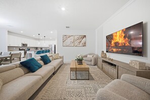 Ein modernes Wohnzimmer mit einer Couch, einem Couchtisch und einem an der Wand befestigten Fernseher.