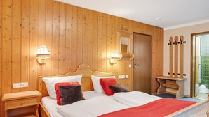 Camera da letto con pannelli in legno, un letto, lampade sui comodini, uno specchio e una panca in legno.