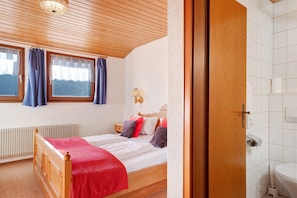 Un dormitorio con una cama de madera, una ventana con cortinas, una mesita de noche y vistas al exterior.