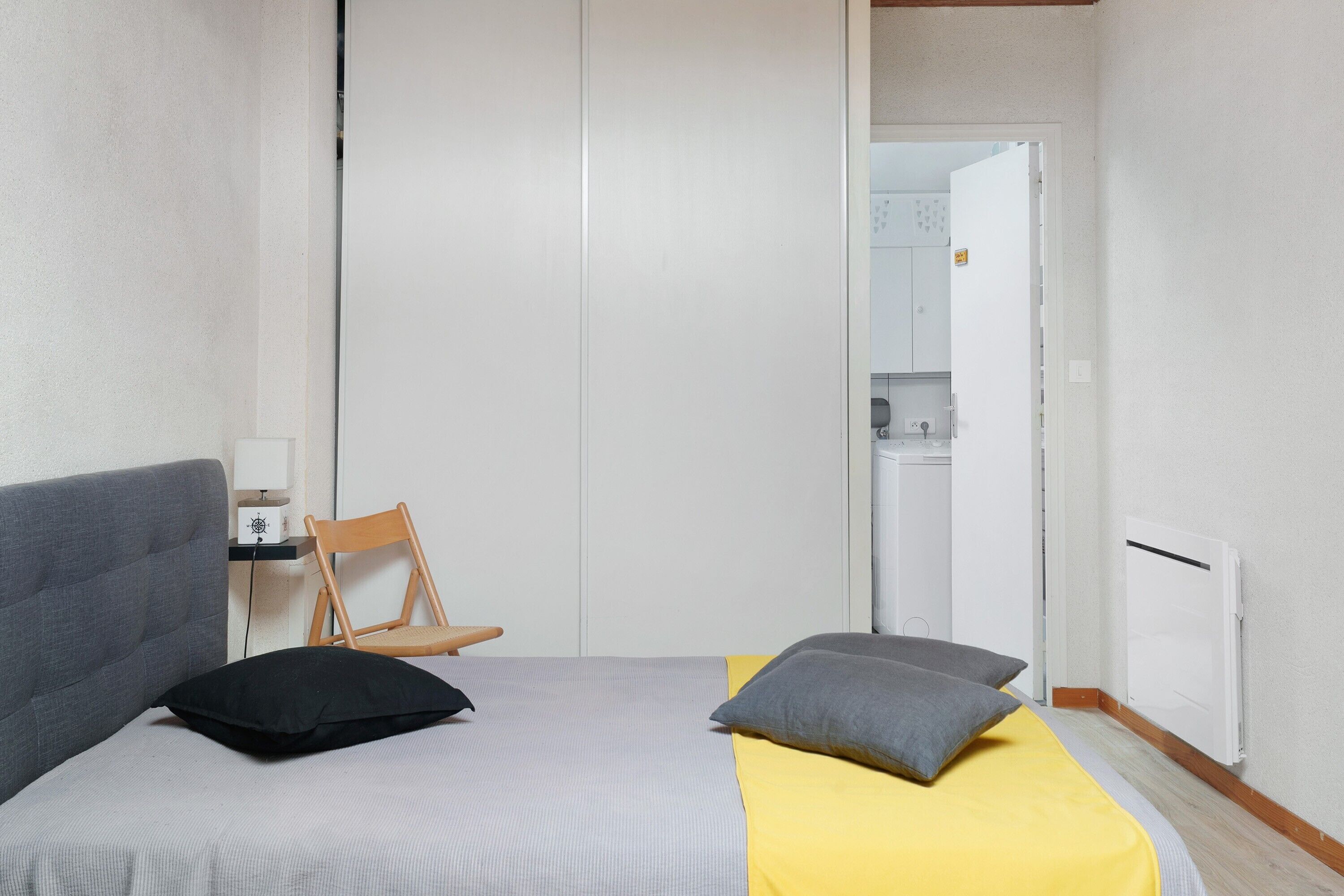 Un dormitorio con cama, una silla, un escritorio y un armario.