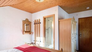 A bedroom with a bed, a wardrobe, a mirror, and a shower. - Room 'Doppelzimmer Superieur 21' with Mountain View, Balcony and Wi-Fi (Wieden)