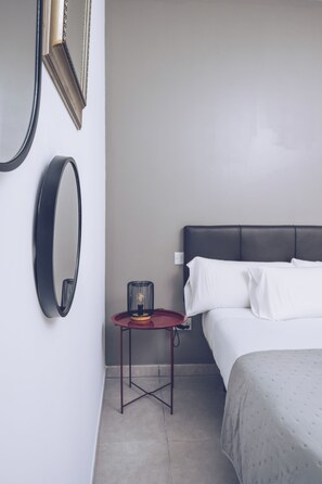 Una camera da letto con un letto, un comodino con una lampada e due specchi fissati alla parete.