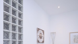 Ein moderner Essbereich mit einem weißen Tisch und Stühlen, einem großen Fenster mit Gittern und einer Uhr, sowie einer Stehlampe.