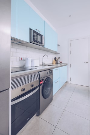 A modern kitchen with a microwave, coffee maker, sink, and washing machine.