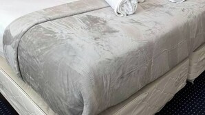 A hotel room with a bed, a nightstand with a lamp, and a door. - Runaway Beach Club 1 Bd Villa (LRW 17101) (Kissimmee)