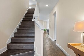 A staircase with dark wooden steps and white railings, leading to a hallway with beige walls and a wooden floor. - Encore Resort 5 Bedroom Home with Pool (2514) (Kissimmee)