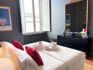 Ein Hotelzimmer mit Bett, Kissen, einem Schminktisch, einem Spiegel und einem Fenster.