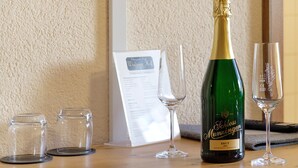 Eine Flasche Schloss Munzingen Brut Wein, zwei leere Weingläser und eine Speisekarte auf einem Holztisch.