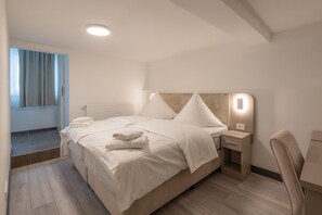 Een moderne hotelkamer met een groot bed, een nachtkastje, een stoel en een raam met gordijnen.