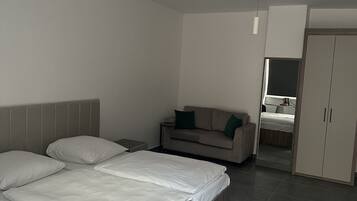 Quarto moderno com cama, sofá, guarda-roupa e espelho.
