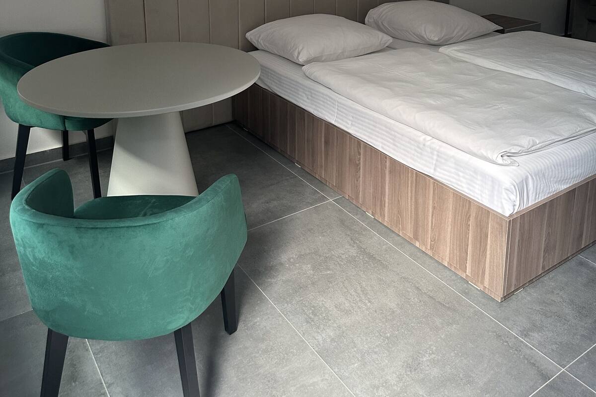 A bedroom with a bed, a round table, and two chairs.
