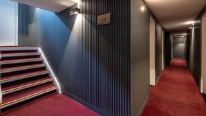 A modern hallway with a red carpet, a staircase with a metal railing, and a sign indicating room numbers 401-407 and 309. - Hotel Johannisberg (Bad Homburg v.d. Hoehe)