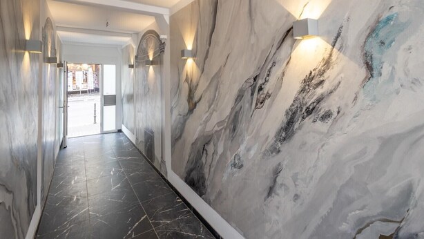 A hallway with marble walls and black tiled flooring. - Hotel Johannisberg (Bad Homburg v.d. Hoehe)