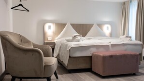 A hotel room with a bed, a chair, and an ottoman. - Hotel Johannisberg (Bad Homburg v.d. Hoehe)