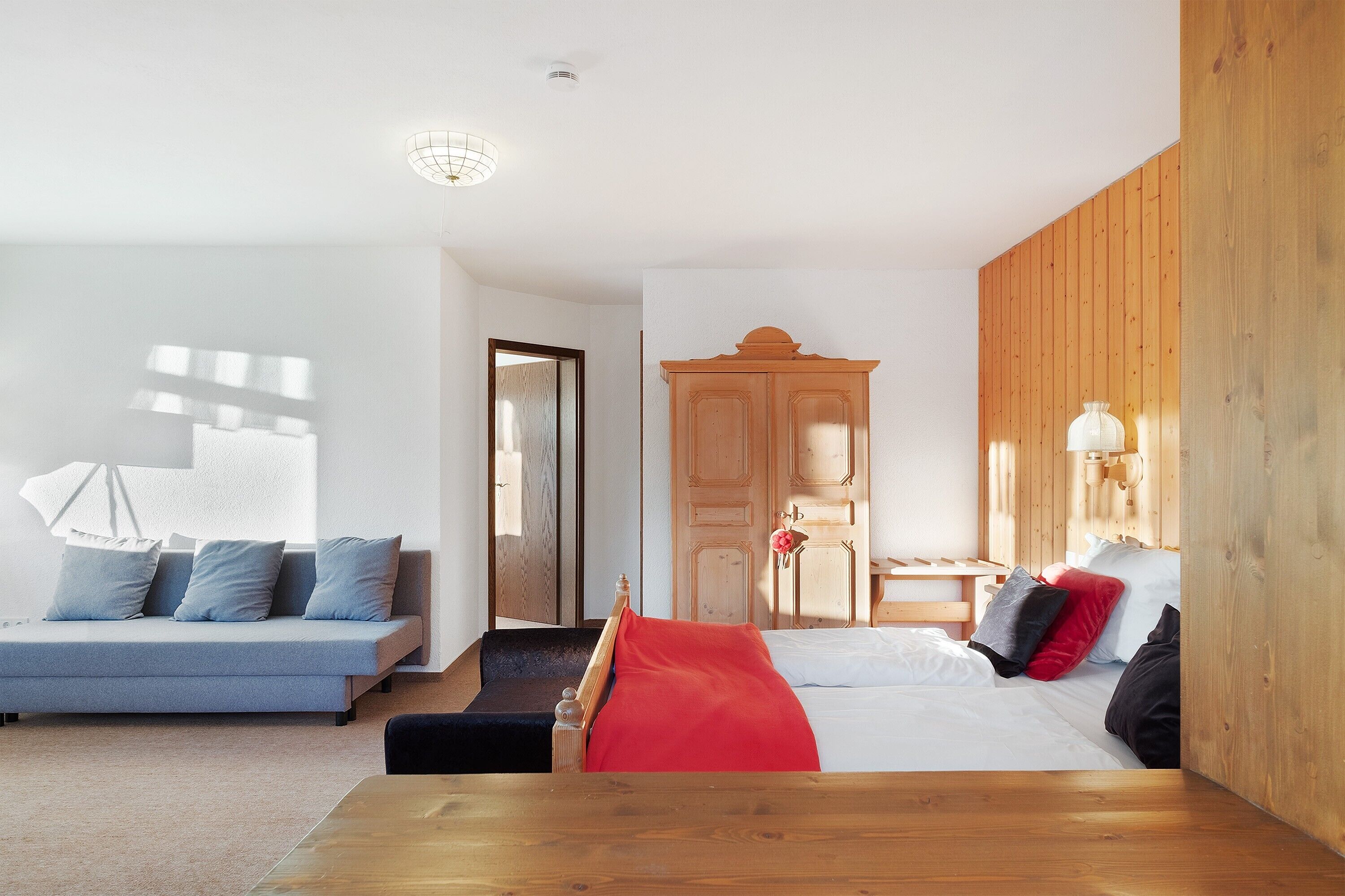 Un dormitorio moderno con cama, sofá, armario de madera y escritorio.