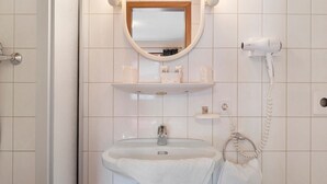 Een badkamer met een wastafel, spiegel, handdoekrek en een haardroger.