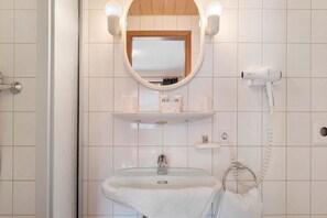 Une salle de bain équipée d’un lavabo, d’un miroir, d’un porte-serviettes et d’un sèche-cheveux.