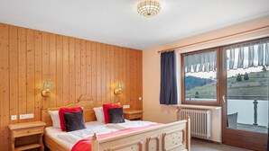 Een slaapkamer met houten lambrisering, een bed, nachtkastjes en een uitzicht door een raam.