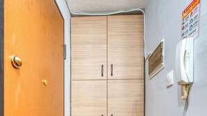Una habitación con un armario de madera, una puerta y un teléfono de emergencia en la pared.