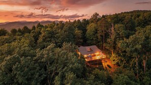 A lodge surrounded by dense forest with a clear view of the mountains in the background. - Panoramic Ridge  | Morganton, GA (Morganton)