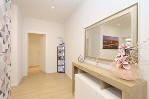 Een moderne badkamer met een grote spiegel, een houten wastafelmeubel en een decoratieve vaas met bloemen.