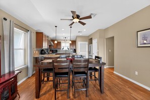 A modern kitchen with wooden cabinets, a dining table with chairs, a ceiling fan, and pendant lights. - Bay-View Delight / Sleeps 8 (Rockport)