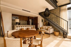 Ein modernes Wohnzimmer mit einem Holzessttisch, Korbstühlen, einer Couch und einer Treppe.