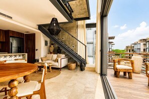 Ein modernes Interieur mit Essbereich, Sofa, Treppe und großen Fenstern.