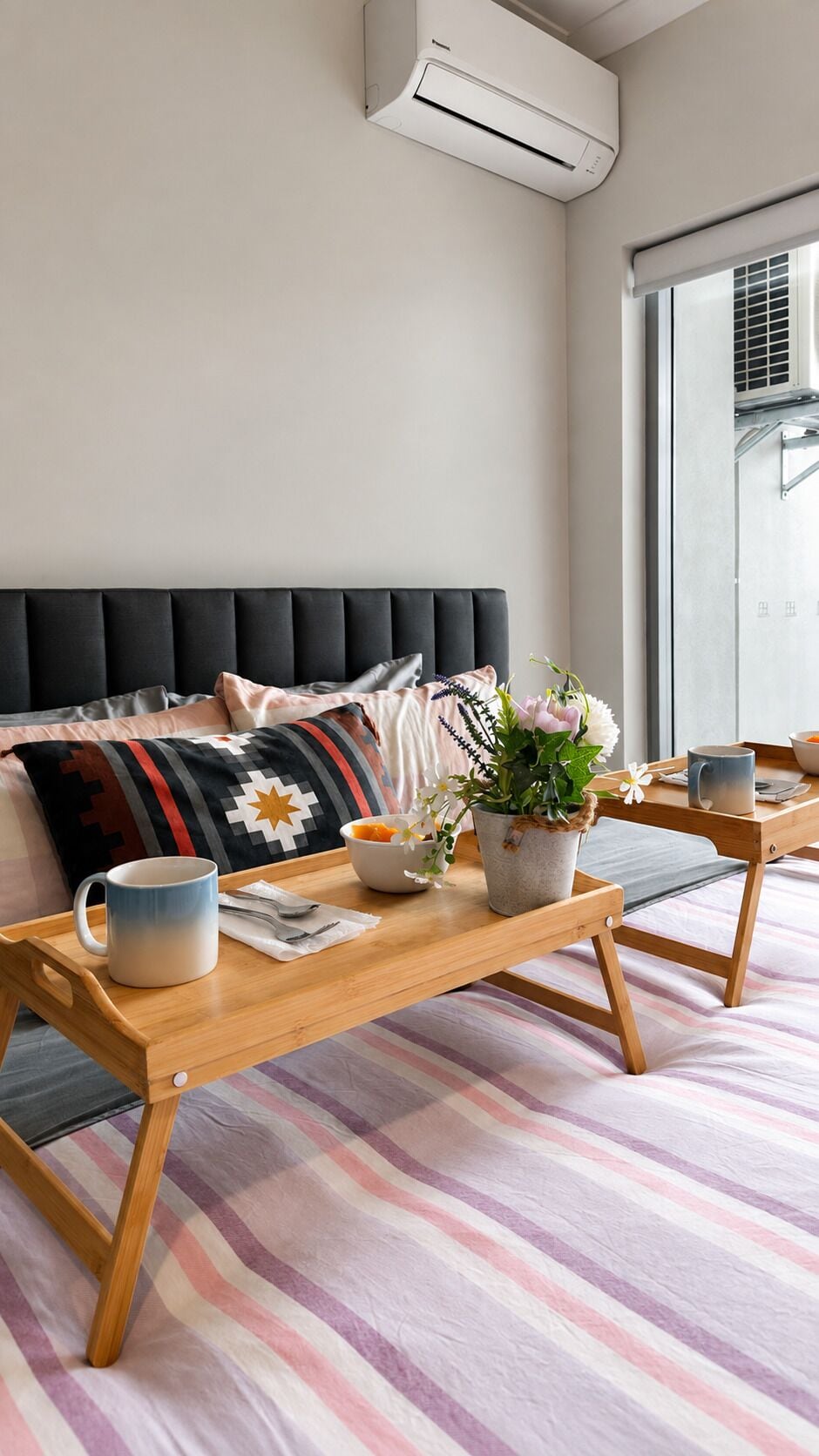 Un dormitorio moderno con una cama, una mesita de noche con una taza, un cuenco de fruta y una planta en maceta.