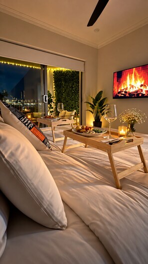 A modern living room with a sofa, a dining table with a vase and candles, a fireplace, and a city view. - Apartment with Balcony & Parking Perth (Perth)