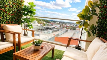 Un balcón con vista a un paisaje urbano, amueblado con un sofá, sillas y una mesa.