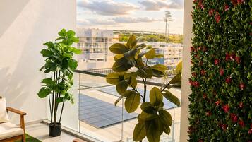 A balcony with a sofa, a coffee table, and potted plants.