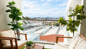 A balcony with a view of the city, furnished with a sofa, chairs, and a table.