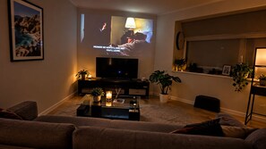 A living room with a flat-screen TV, a coffee table with candles, and a sofa. - Apartment with Balcony & Parking Perth (Perth)