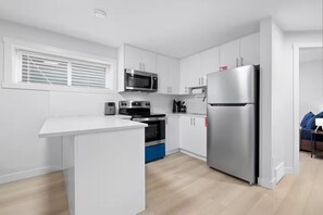 A modern kitchen with white cabinetry, stainless steel appliances, and a central island.