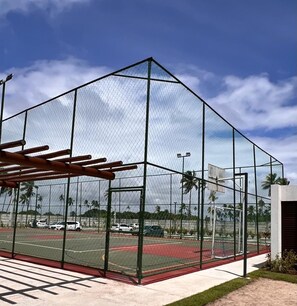 A sports facility with a fenced area, a basketball court, and a netted structure. - FlatManaBeach (Ipojuca)