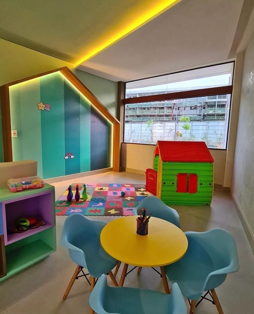 A children's play area with a colorful play mat, a small house, and a table with chairs.