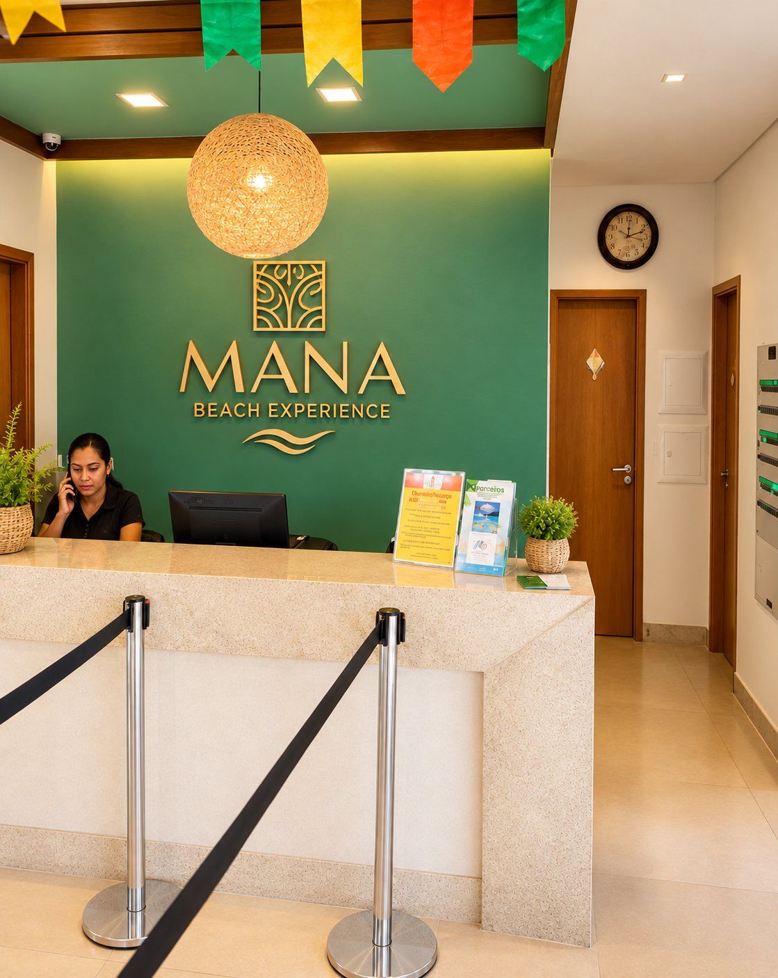 A reception desk with a sign reading 'MANA BEACH EXPERIENCE' and a clock on the wall.