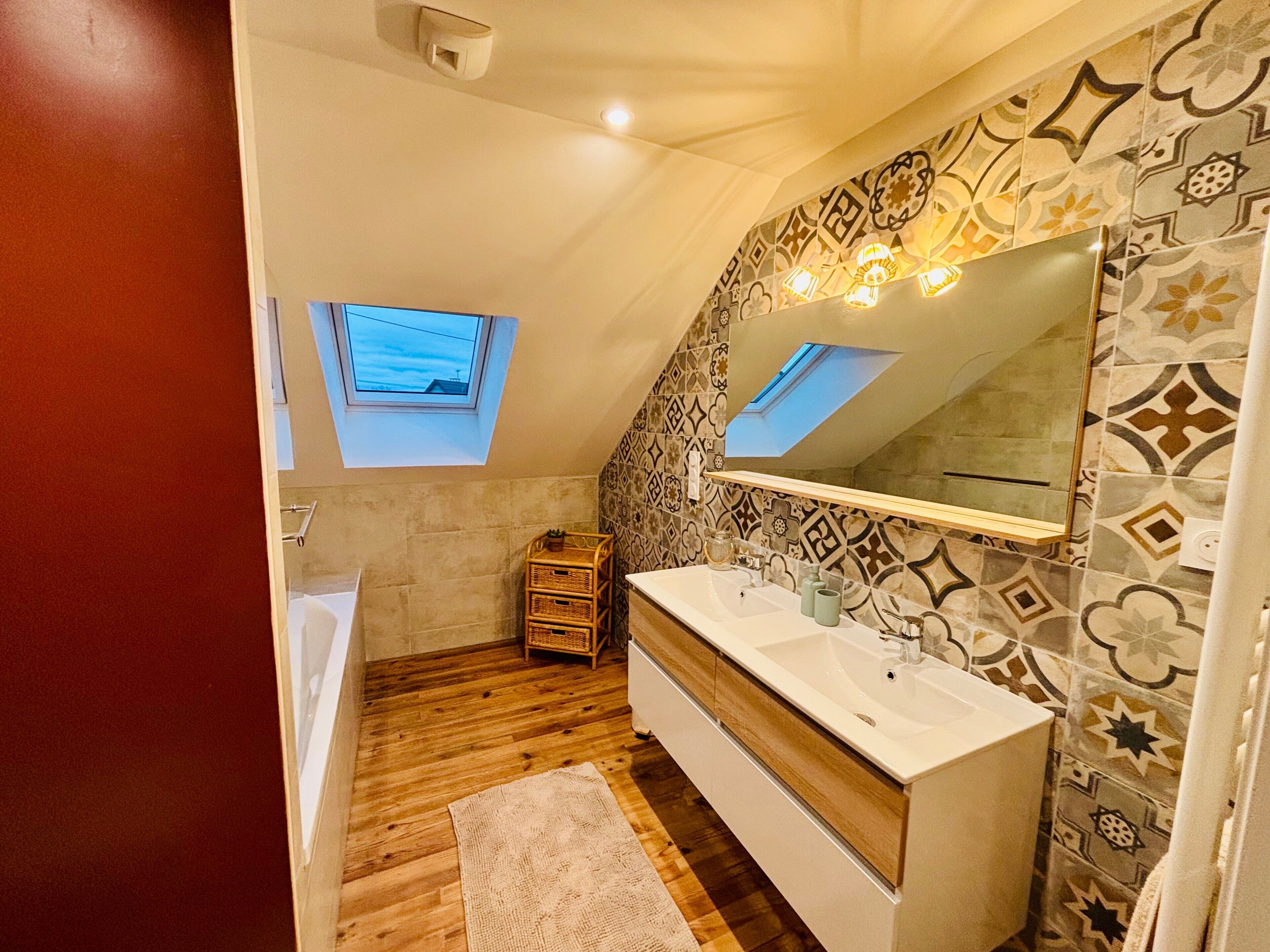 Une salle de bain moderne dotée d’un puits de lumière, d’un grand miroir et d’un meuble-lavabo en bois.