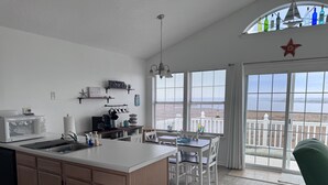 Een keuken met een groot eiland, een eetgedeelte met uitzicht en een balkon met een balustrade.