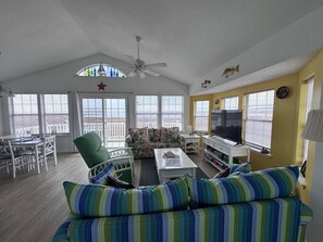 A spacious living room with a large sofa, a dining area with a table and chairs, a television, and a ceiling fan. - Volare at the Sea
3-bedroom townhome with Ocean View and Pool (North Topsail Beach)