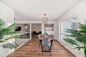 Um interior moderno com uma mesa de jantar de madeira, cadeiras e guarda-corpo de vidro.
