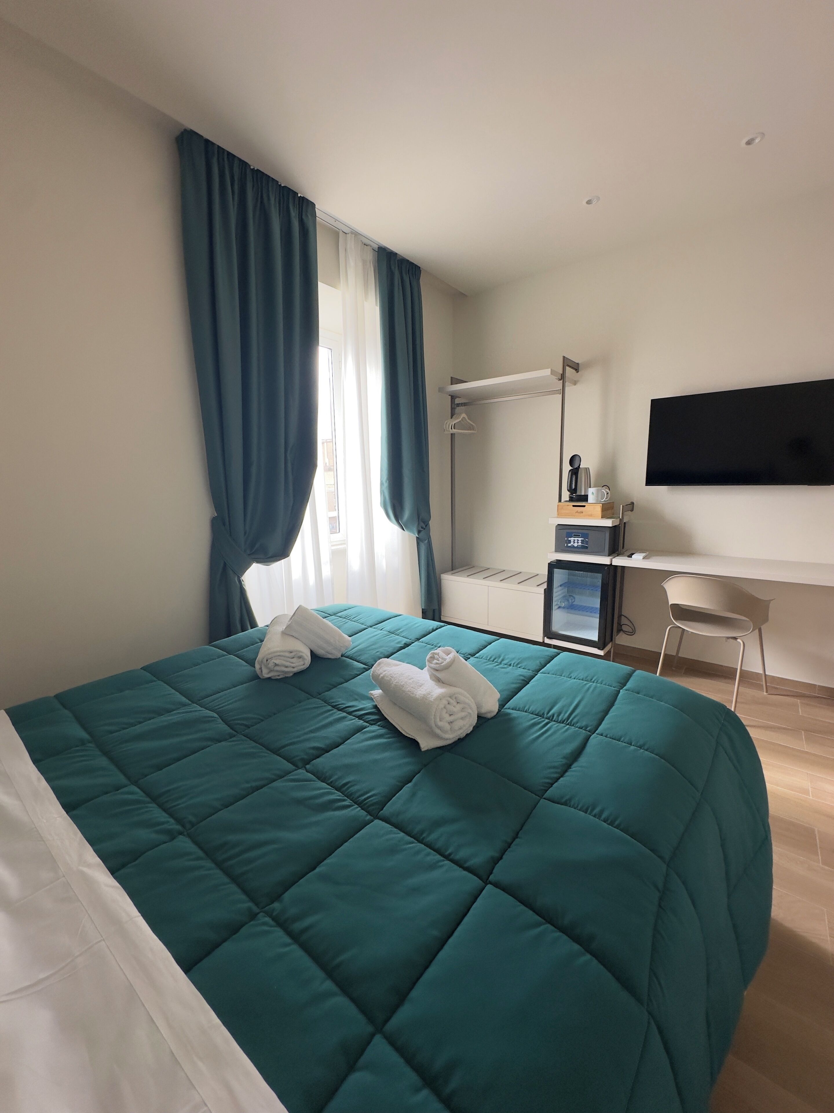 Habitació d'hotel amb llit, escriptori, televisió i zona de dutxa.