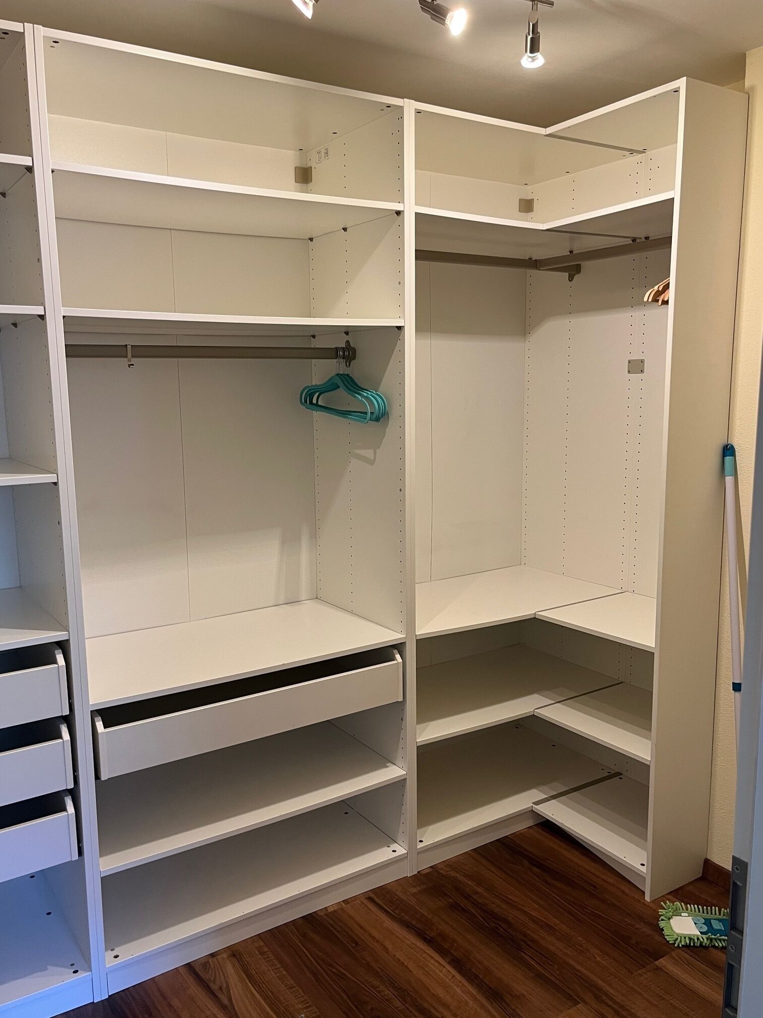 Ein begehbarer Kleiderschrank mit offenen Regalen, einer Kleiderstange und einer ausziehbaren Schubladeneinheit.
