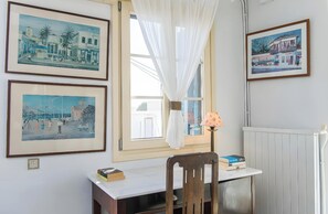 A room with a desk, chair, framed pictures, and a window with curtains. - Apartment in 'Unit 6' Hotel with Private Terrace, Wi-Fi and Air Conditioning (Egina)