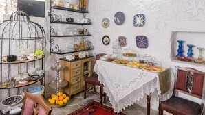 A room with a dining table set for a meal, surrounded by shelves with various kitchenware and decorative plates.