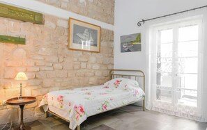 A bedroom with a bed, a lamp, a window with curtains, and a stone wall. - Apartment in 'Unit 6' Hotel with Private Terrace, Wi-Fi and Air Conditioning (Egina)