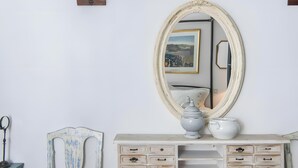 A white dresser with multiple drawers, a large mirror, and a vase.