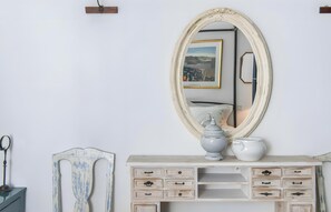 Une commode blanche avec de nombreux tiroirs, un grand miroir et un vase.